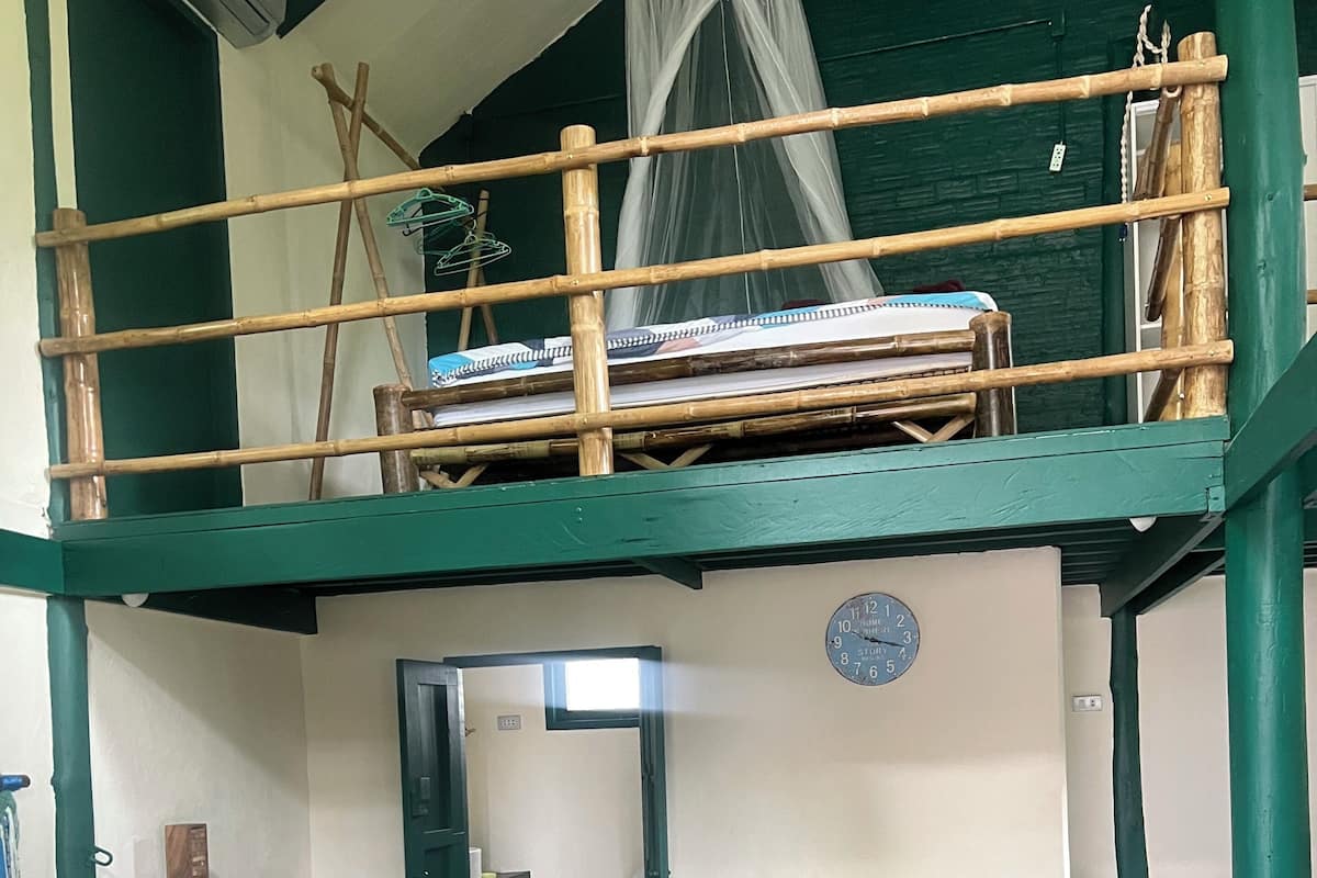 Ein Zimmer mit Etagenbett, einer Schlafcouch, einem Tisch und einem Stuhl.