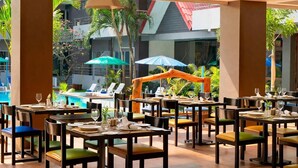 Restaurante con terraza al aire libre, vistas a una piscina y jardín, con mobiliario moderno y un diseño contemporáneo.