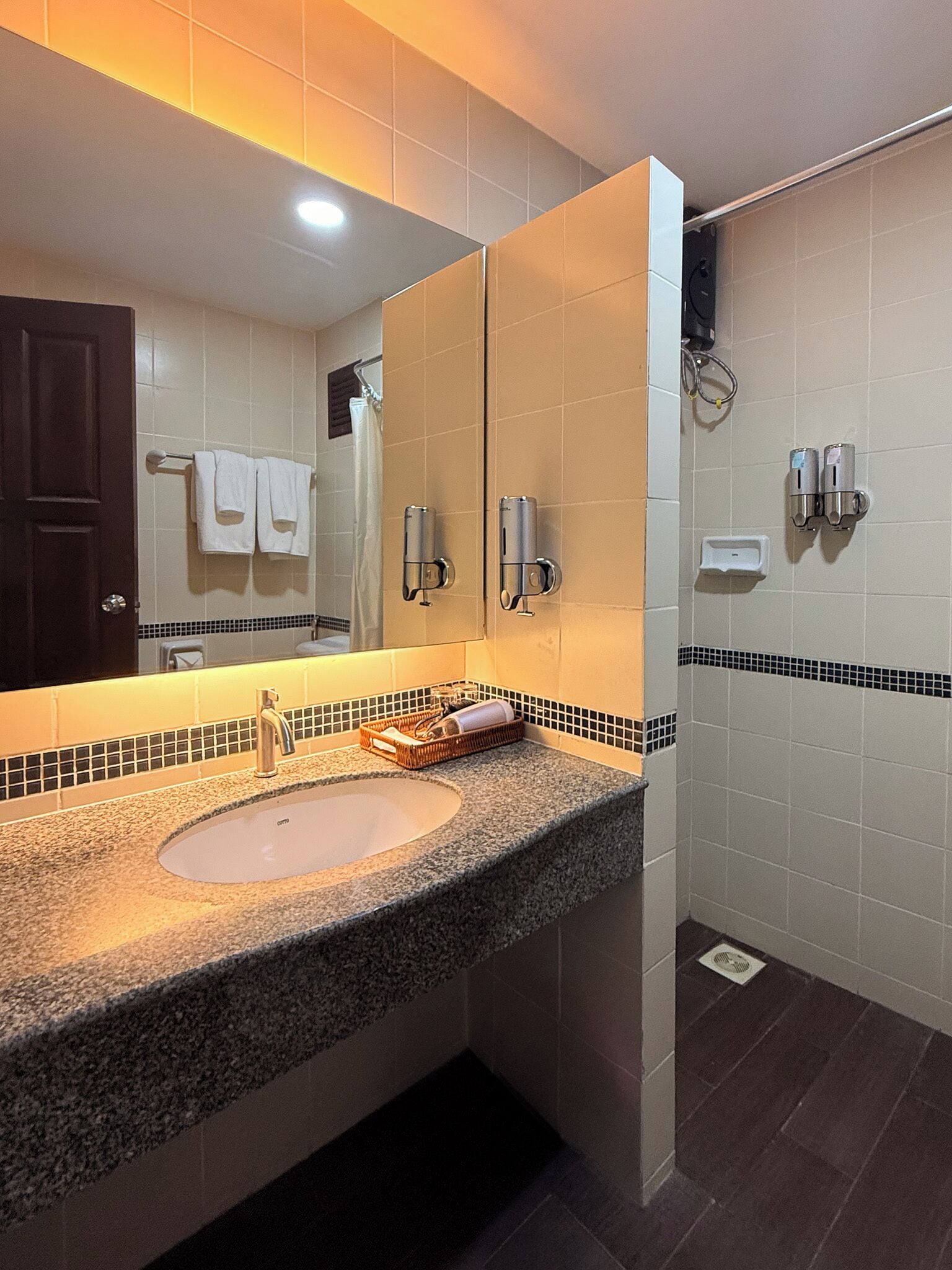 Une salle de bain équipée d’un lavabo, d’un miroir, d’un porte-serviettes et de deux sèche-mains.