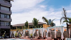 A swimming pool with lounge chairs and umbrellas, surrounded by buildings and palm trees. - The Holiday Resort Pattaya (Pattaya)