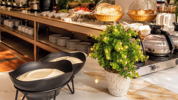 A buffet setup with various food items, a coffee station, and a decorative plant in the foreground. - The Holiday Resort Pattaya (Pattaya)