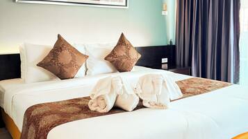 A hotel room with a bed, pillows, a blanket, a cityscape painting, and a window with curtains.
