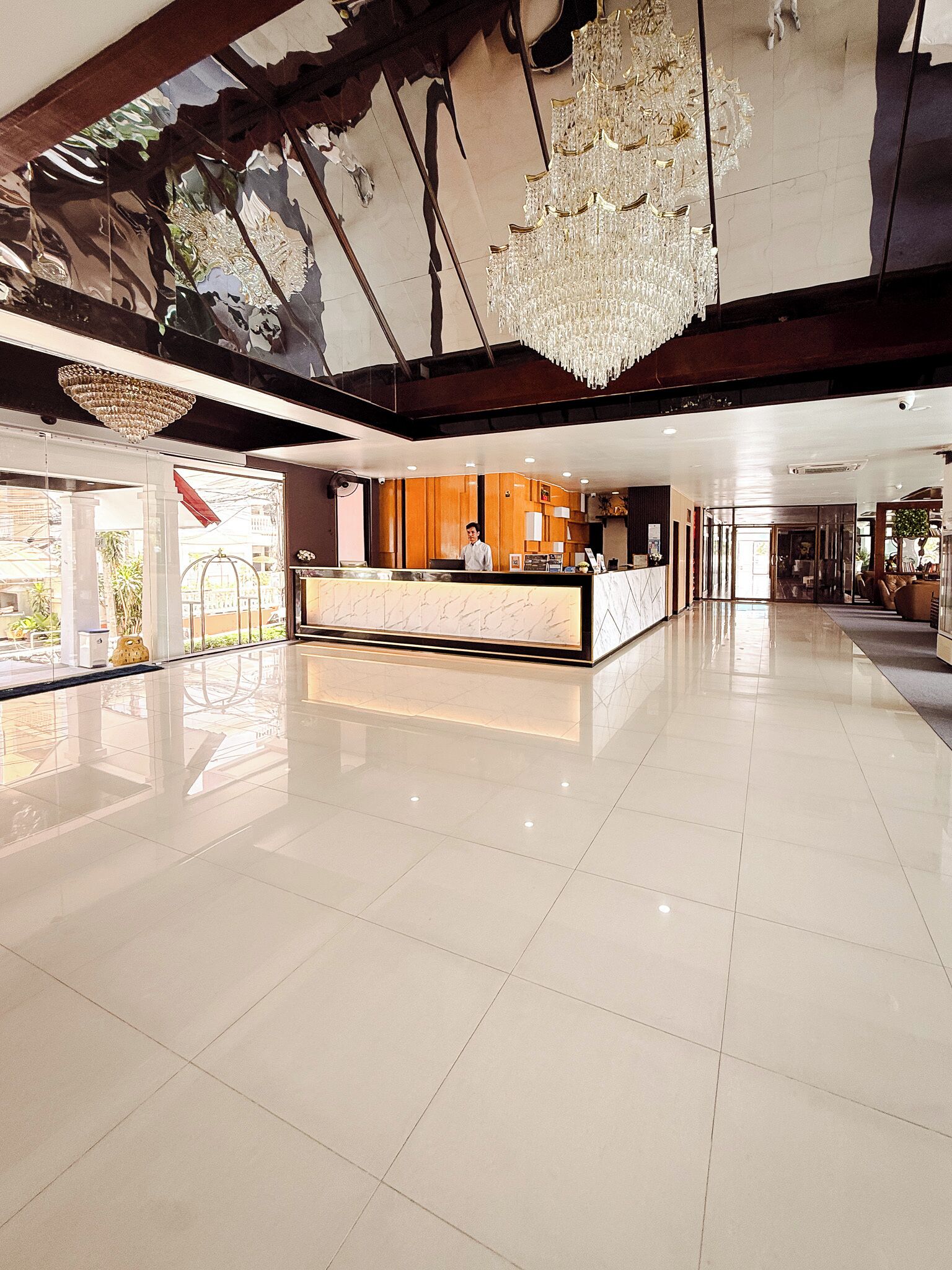 A spacious lobby with a reception desk, a chandelier, and a large window.