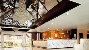 A modern lobby with a reception desk, two large woven coffee tables with plants, and a view of the outside. - The Holiday Resort Pattaya (Pattaya)