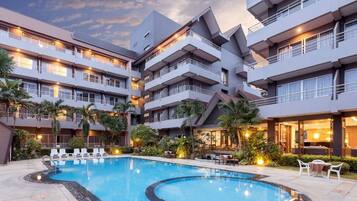 Ein Hotel mit Schwimmbad, mehreren Balkonen und Sitzgelegenheiten im Freien.