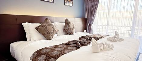 Habitación de hotel con una cama grande, un cabecero, una mesita de noche y una ventana con cortinas.