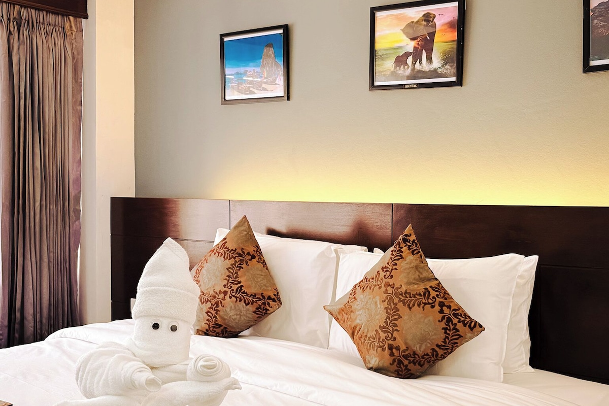 A hotel room with a large bed, a headboard, and two framed pictures on the wall.
