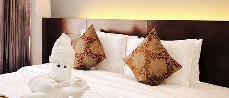 A hotel room with a large bed, a headboard, and two framed pictures on the wall.