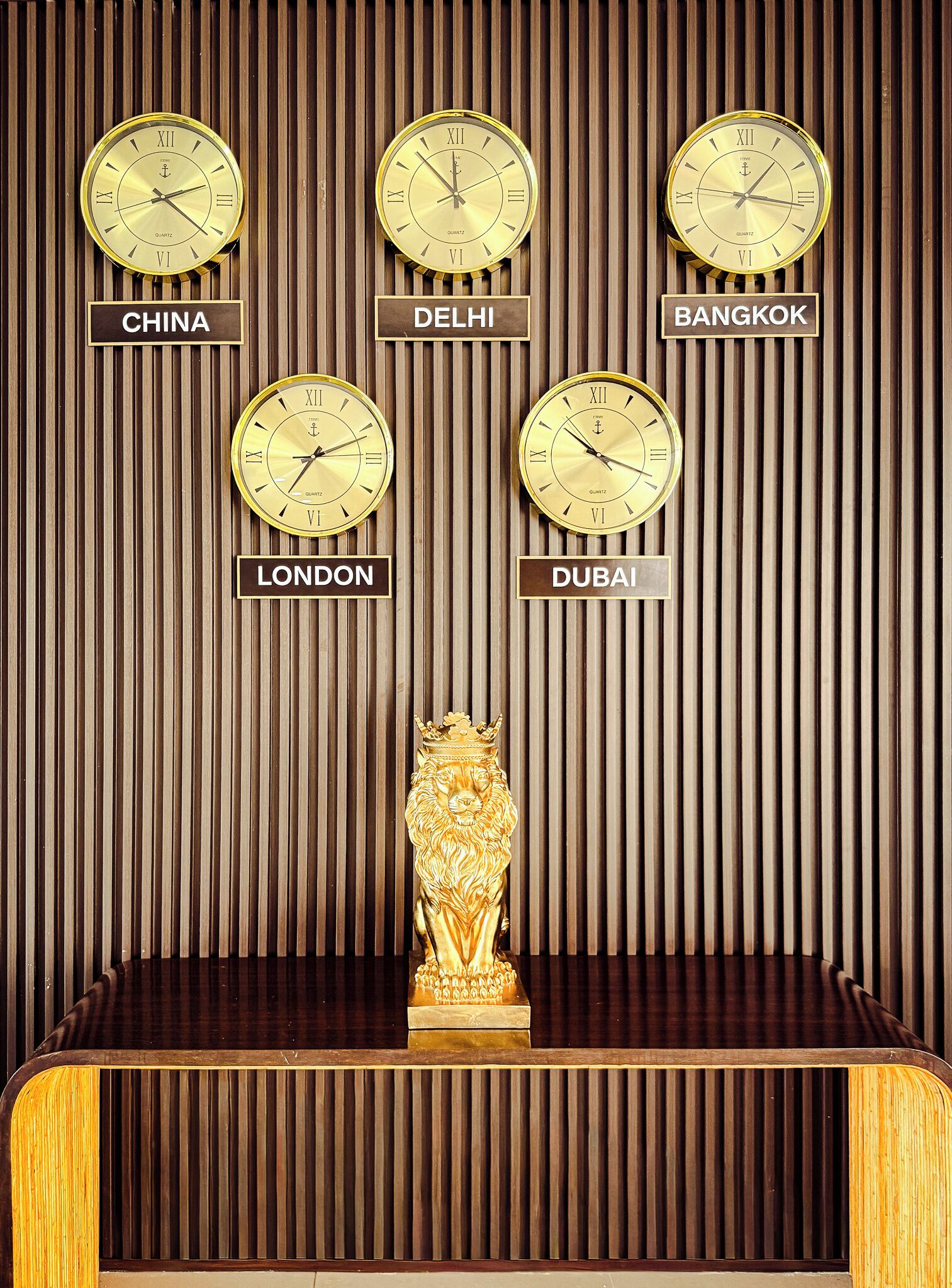 Un mur orné d’horloges indiquant le nom de différentes villes, ainsi qu’une statue de lion en or.