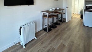 A modern kitchen with a built-in oven, a dining area with a table and chairs, and a flat-screen TV mounted on the wall. - A secluded and tranquil cabin ideal for exploring Lewis and Harris (Isle of Lewis)