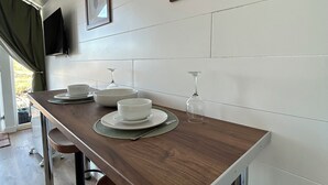 A dining area with a wooden table, chairs, and a television mounted on the wall. - A secluded and tranquil cabin ideal for exploring Lewis and Harris (Isle of Lewis)