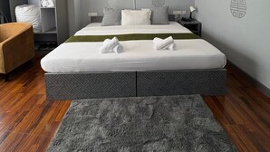 A modern hotel room with a large bed, a wardrobe, a desk, and a chair. - The Gochuka Hotel (Thimphu)