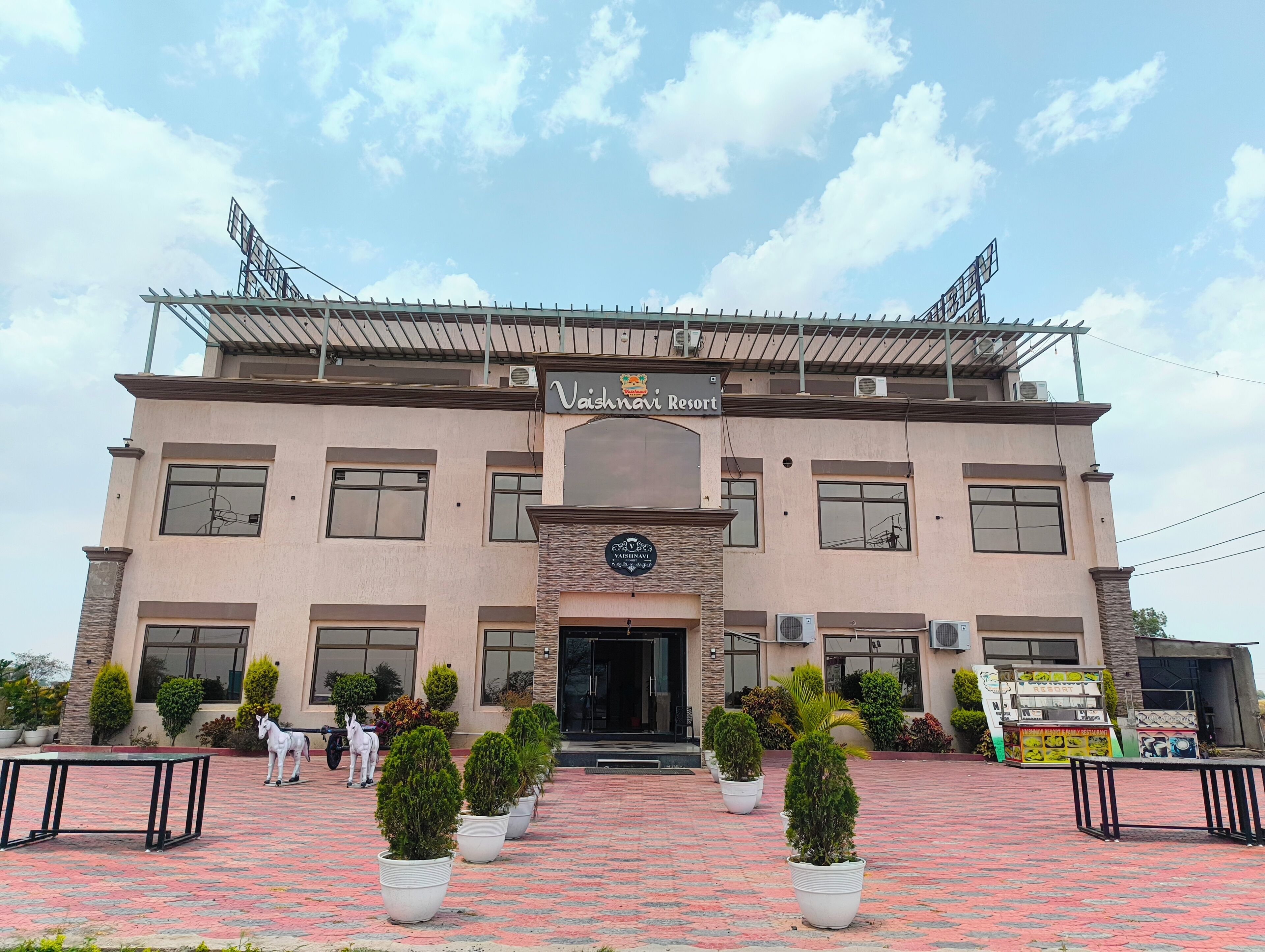 A building with a sign reading 'Vaishnavi Resort' and a sign for 'Vaishnavi Yoga & Wellness.'