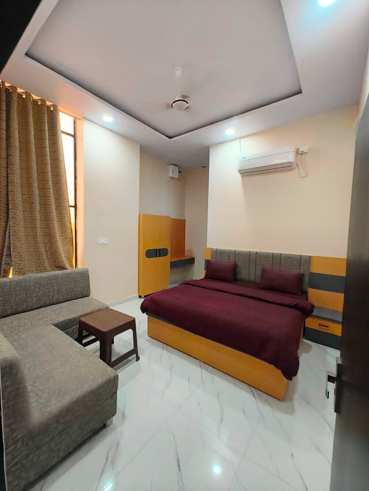 A modern hotel room with a bed, sofa, and a small table.