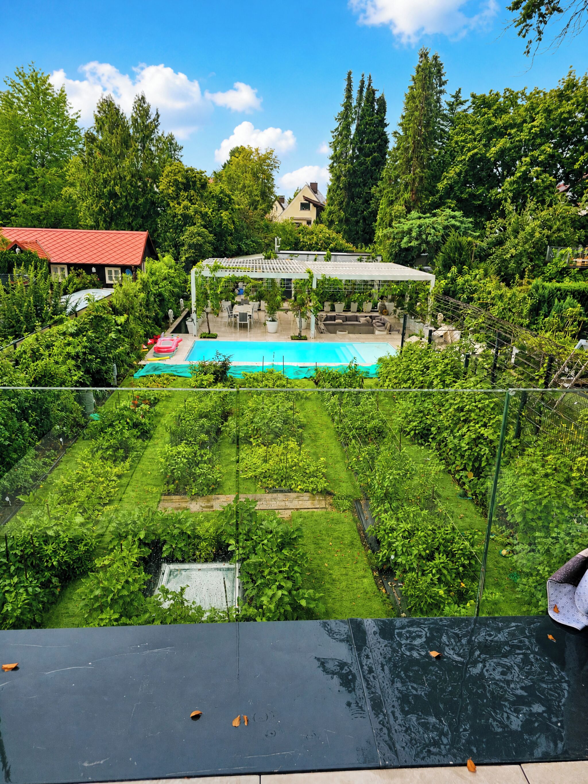 Ein Wohngebiet mit Schwimmbad, Garten und überdachter Terrasse.