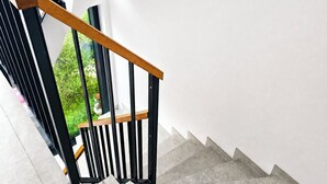 Una escalera con barandilla de madera y balaustradas negras, que conduce a una pared blanca.