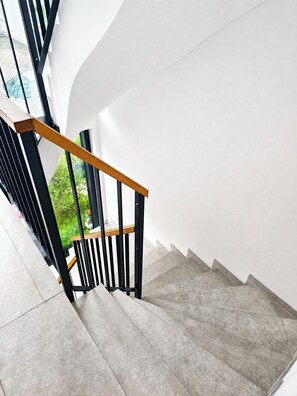Eine Treppe mit hölzernem Geländer und schwarzen Spindeln, die zu einer weißen Wand führt.