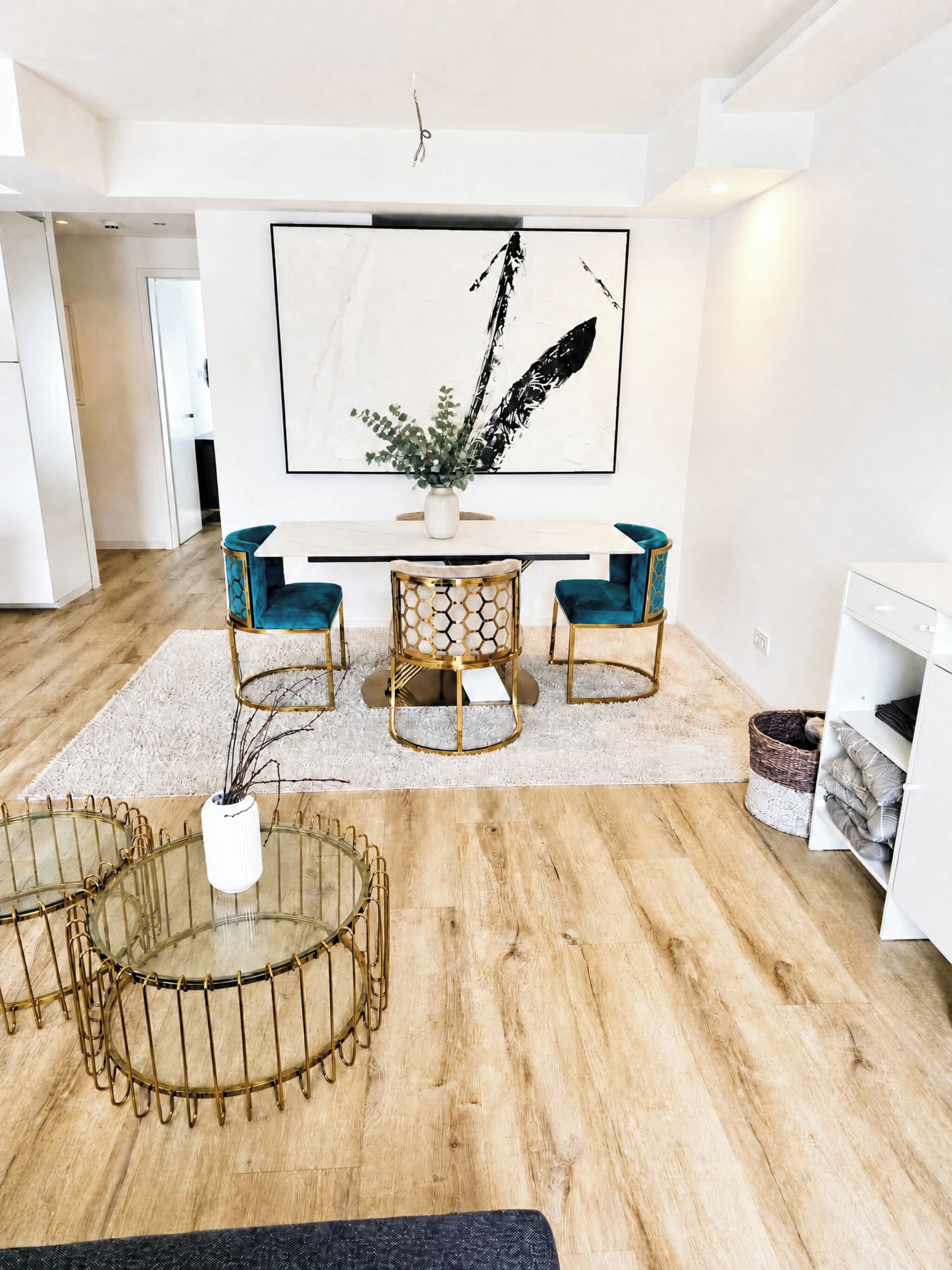 Ein modernes Wohnzimmer mit Essbereich, einem großen abstrakten Gemälde und einem runden Couchtisch mit Glasplatte.