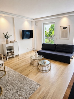 A modern living room with a sofa, a coffee table, and a TV mounted on the wall.