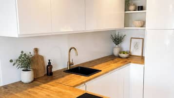 A modern kitchen with white cabinetry, a wooden countertop, and a black induction cooktop.