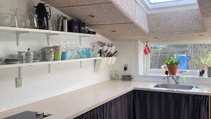 Eine moderne Küche mit Oberlichter, weißen Arbeitsplatten und einer dunklen Kücheninsel mit Sockel.