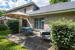 A residential patio with a table and chairs, a covered umbrella, and a large window. - 3-Guest Apartment with Terrace in Saumur (Saumur)