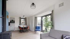 Een moderne woonkamer met een bank, eettafel, stoelen en een groot raam met gordijnen.