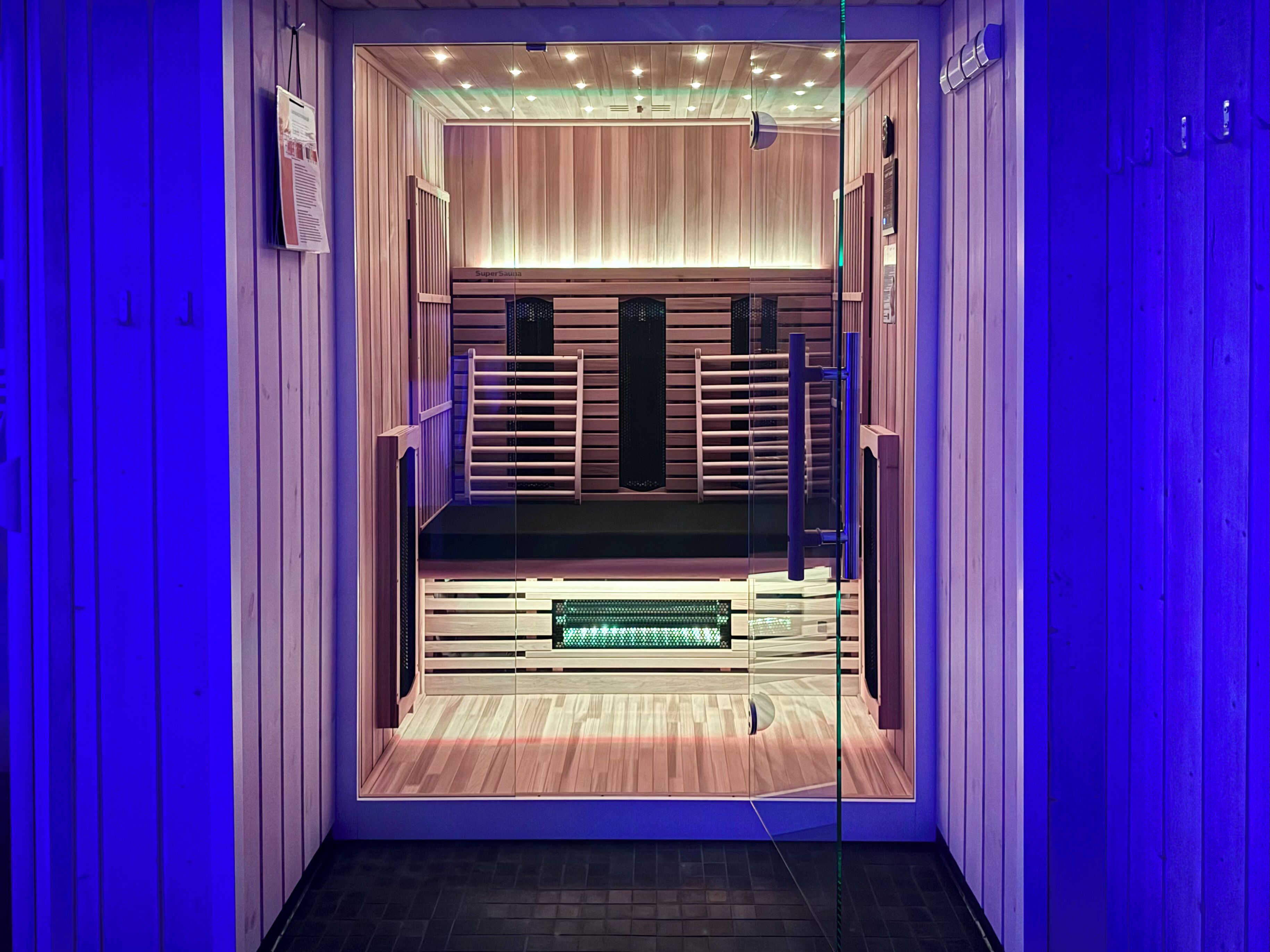 A modern, well-lit room with wooden paneling, a bench, and a glass partition.