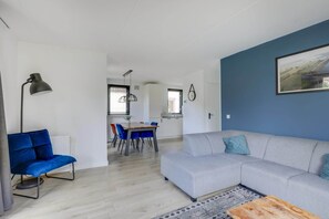Una sala de estar moderna con un sofá, una mesa de comedor y una silla azul.