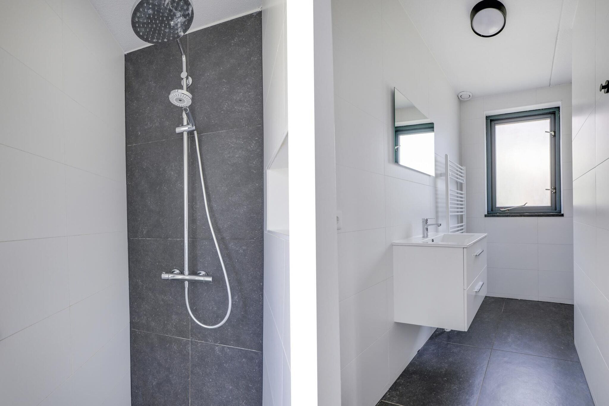 Een moderne badkamer met een douche, wastafel en spiegel.