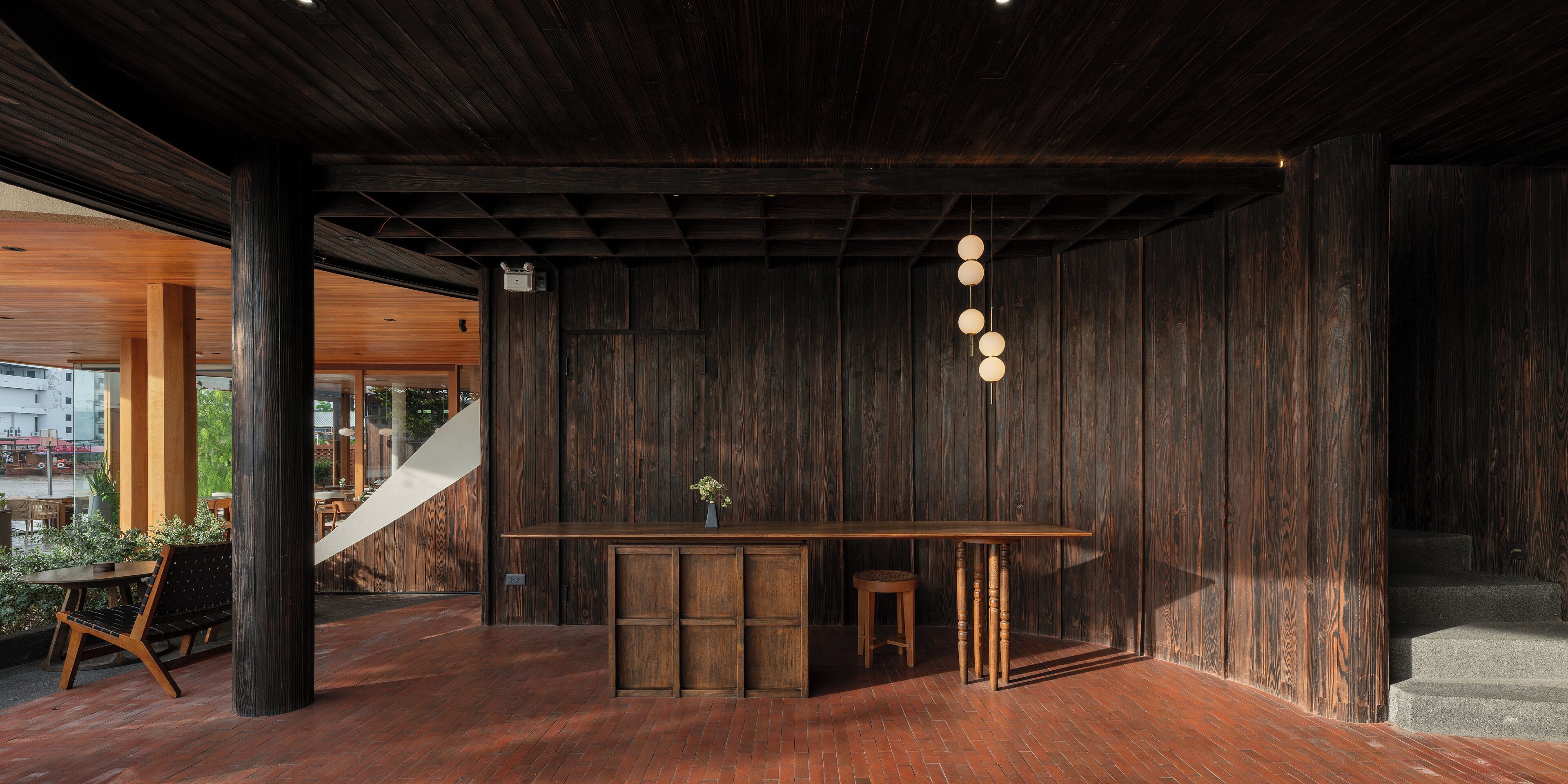 A modern interior with a wooden bar area, a staircase, and a view of the outside.
