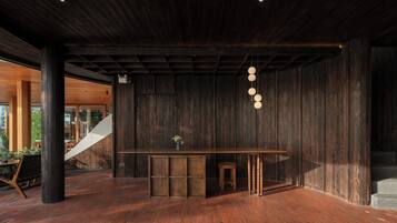 A modern interior with a wooden bar area, a staircase, and a view of the outside.