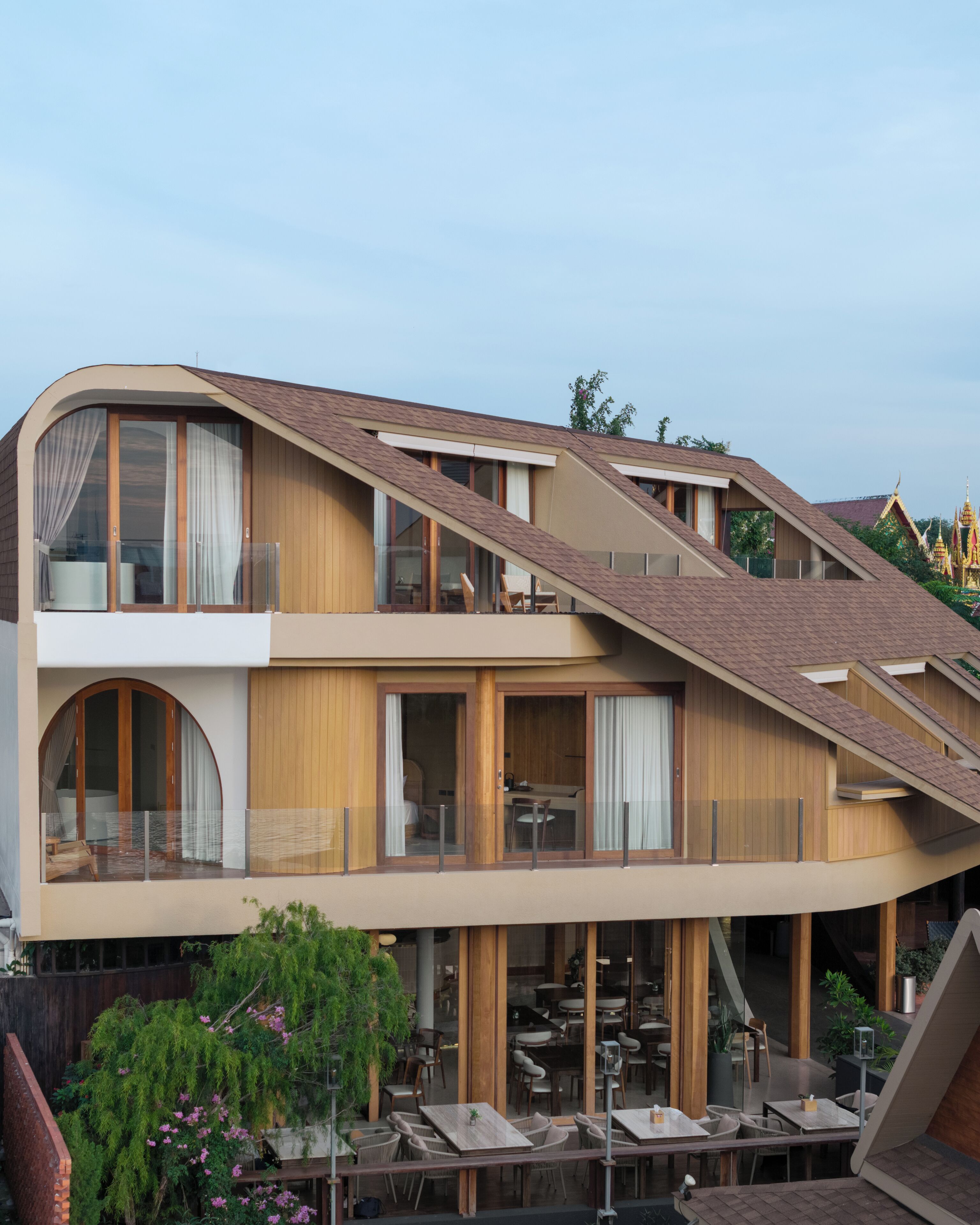 A modern building with a sloped roof, large windows, and a dining area with outdoor seating.