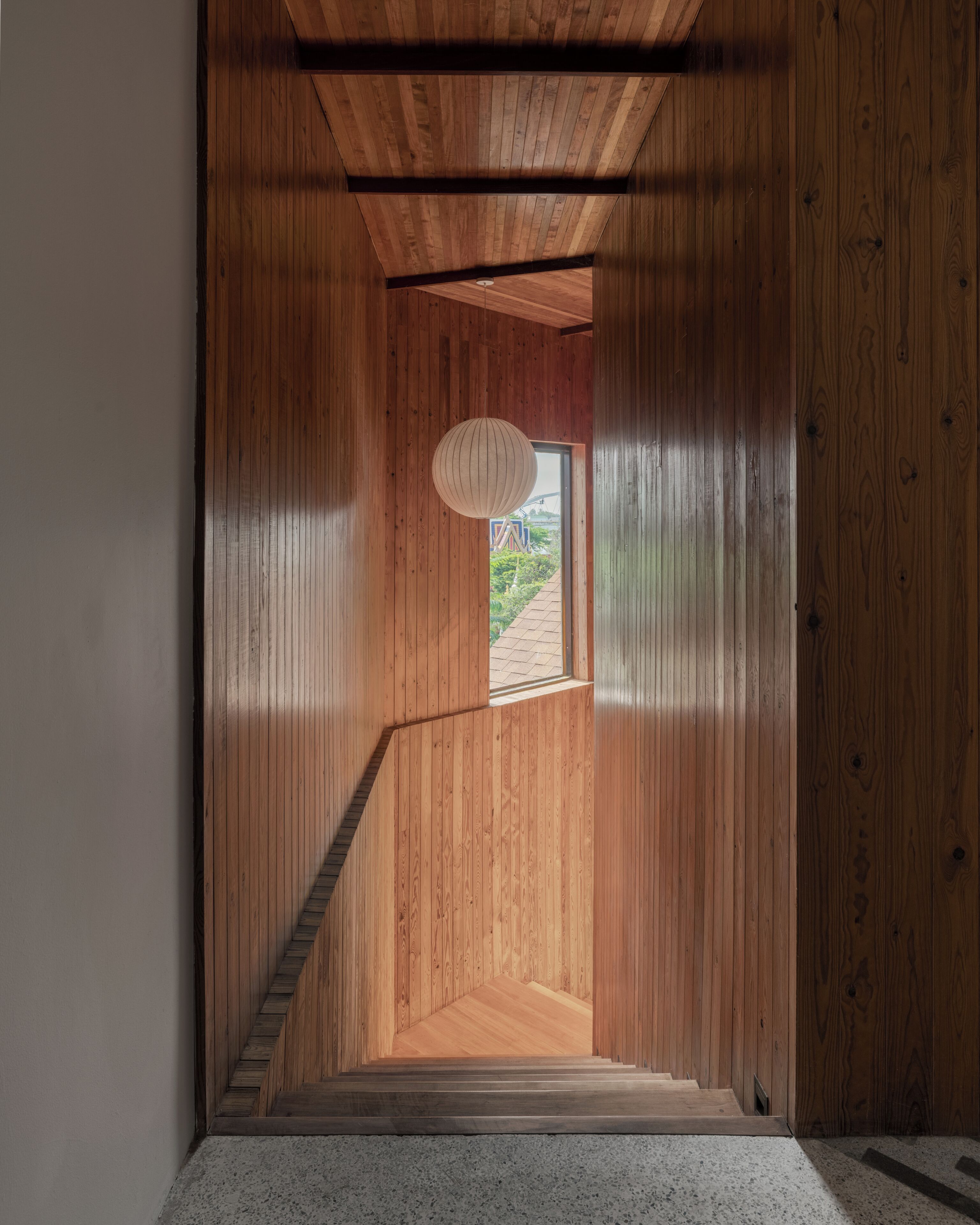 Una escalera de madera que lleva a una puerta con vistas a la vegetación.