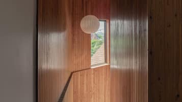 Una escalera de madera que lleva a una puerta con vistas a la vegetación.