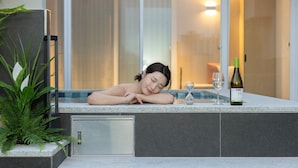 Een wellnessruimte met een bubbelbad, een fles wijn en een glas water.