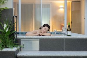 A spa area with a hot tub, a bottle of wine, and a glass of water. - Daejeon Anook Hotel Yuseong Oncheon Station (Daejeon)