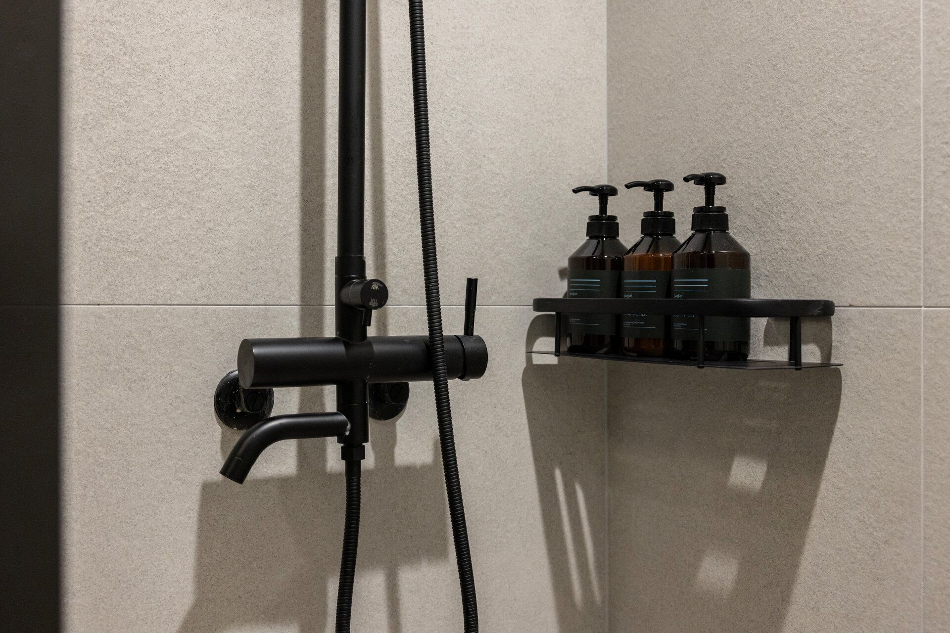 Une salle de bain avec une douche, un robinet et une étagère remplie de bouteilles.