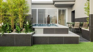 Een modern zwembadterras met glazen inloop, omgeven door groen en een zithoek met stoelen.