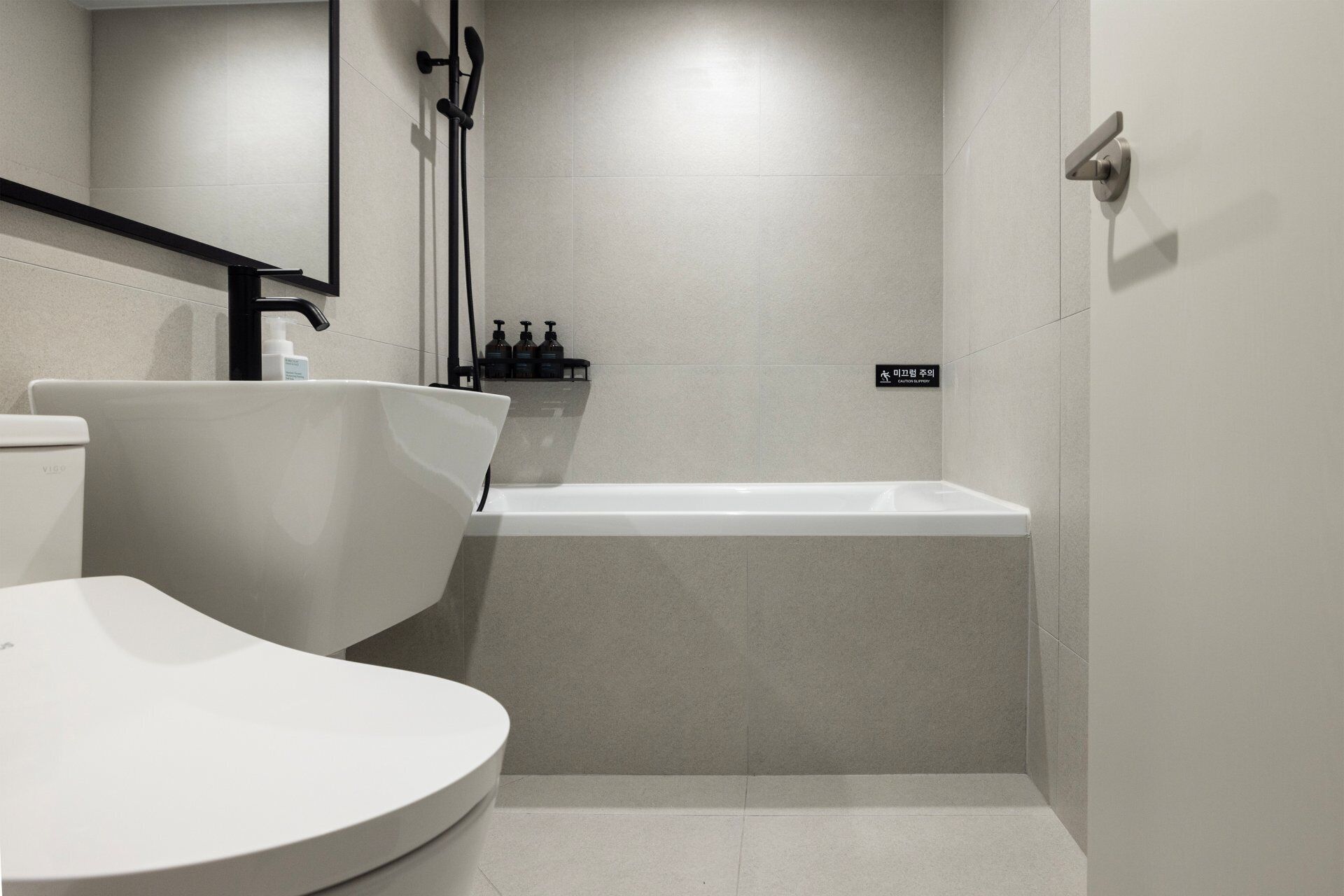 Een moderne badkamer met toilet, bad en douche.