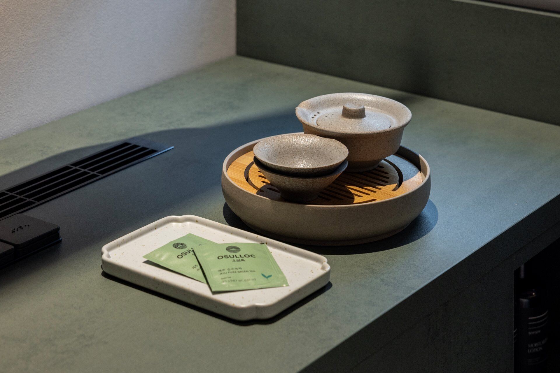A kitchen counter with a tea set, a kettle, and a teapot.