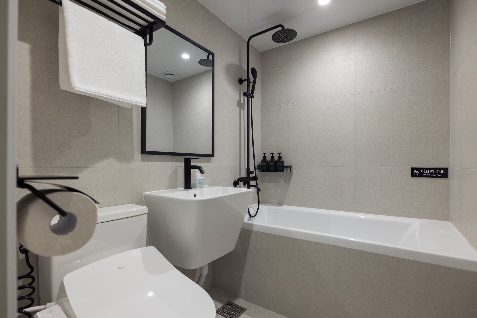 A modern bathroom with a toilet, sink, mirror, shower, and bathtub.
