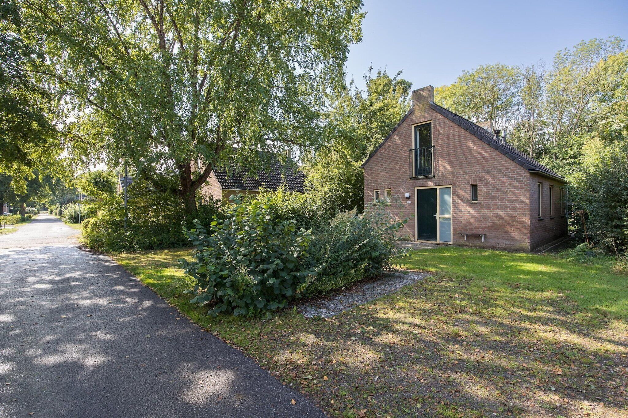 Een klein, wit gevelhuis met schuin dak, een voordeur en een raam.