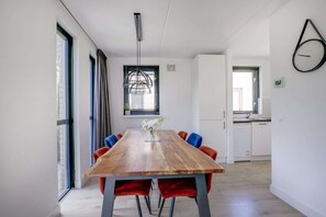 A modern kitchen with white cabinets, a built-in oven, and a window. - Lakeside Retreat with Garden in Ewijk (Ewijk)