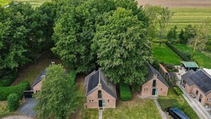 Zona residencial con un árbol grande, varias casas de ladrillo y campos aledaños.
