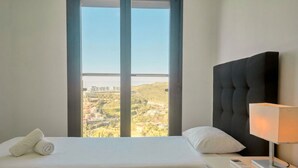 Une chambre d’hôtel avec un lit, une lampe de chevet, une télécommande et une fenêtre donnant sur un paysage.