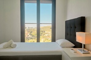 Ein Hotelzimmer mit Bett, Nachttischlampe, Fernbedienung und Fenster mit Landschaftsblick.