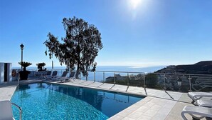 Un ciel d’un bleu éclatant, une piscine avec des chaises longues et une vue sur la mer.
