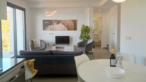 Un salon moderne comprenant un canapé, des fauteuils, une table à manger, un téléviseur et une plante.