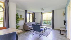 Un salon moderne comprenant un canapé, une table à manger, une chaise et un téléviseur.